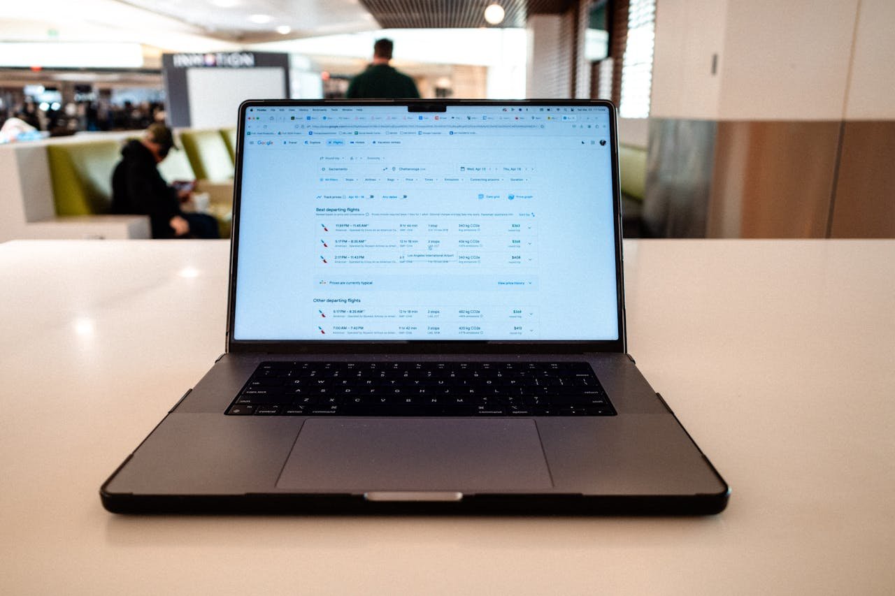 why-choose-us A modern laptop displaying flight schedules on a white table in an airport lounge.