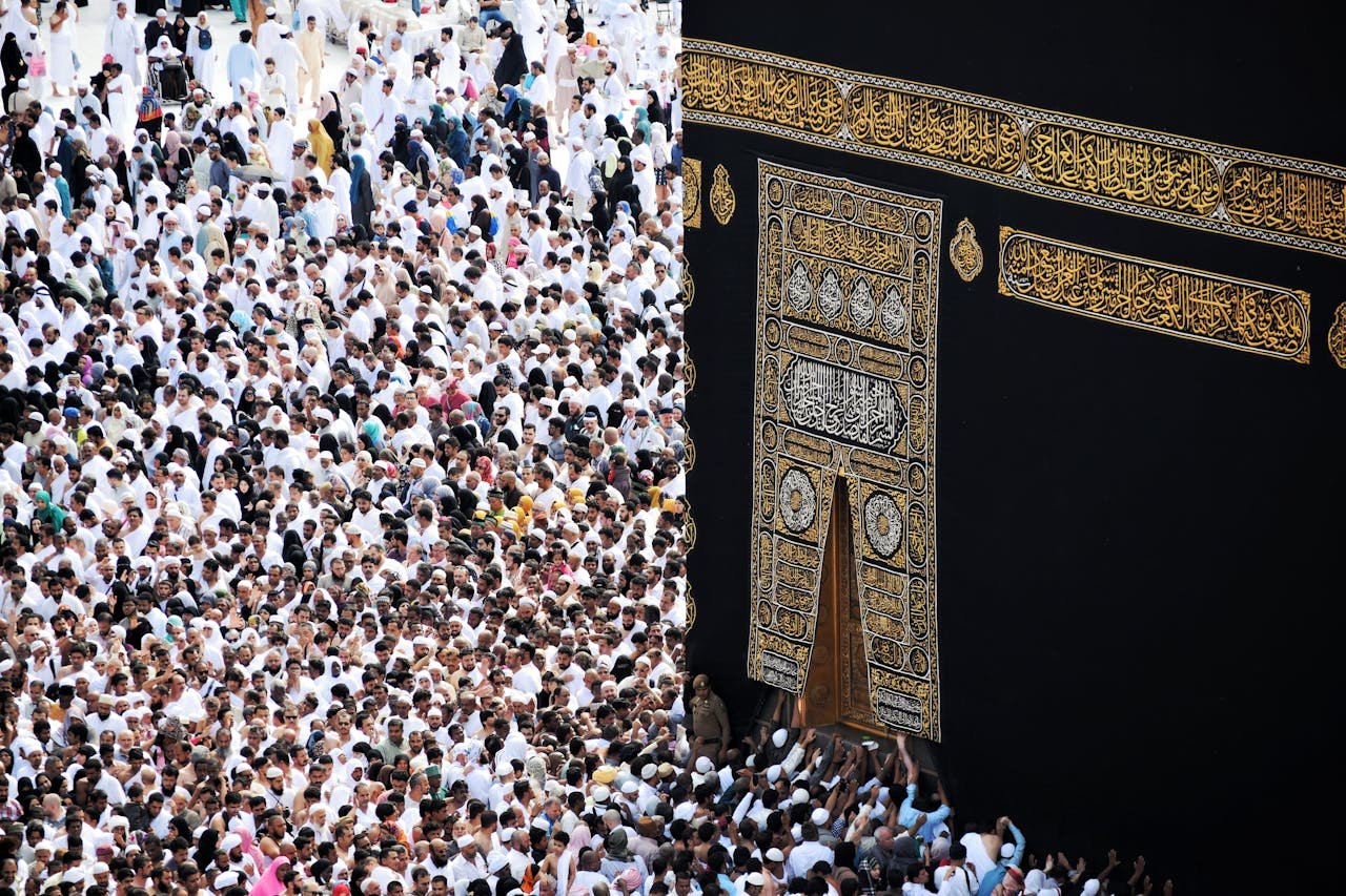 team-01 Mass of pilgrims in traditional attire at Kaaba during the Hajj pilgrimage.