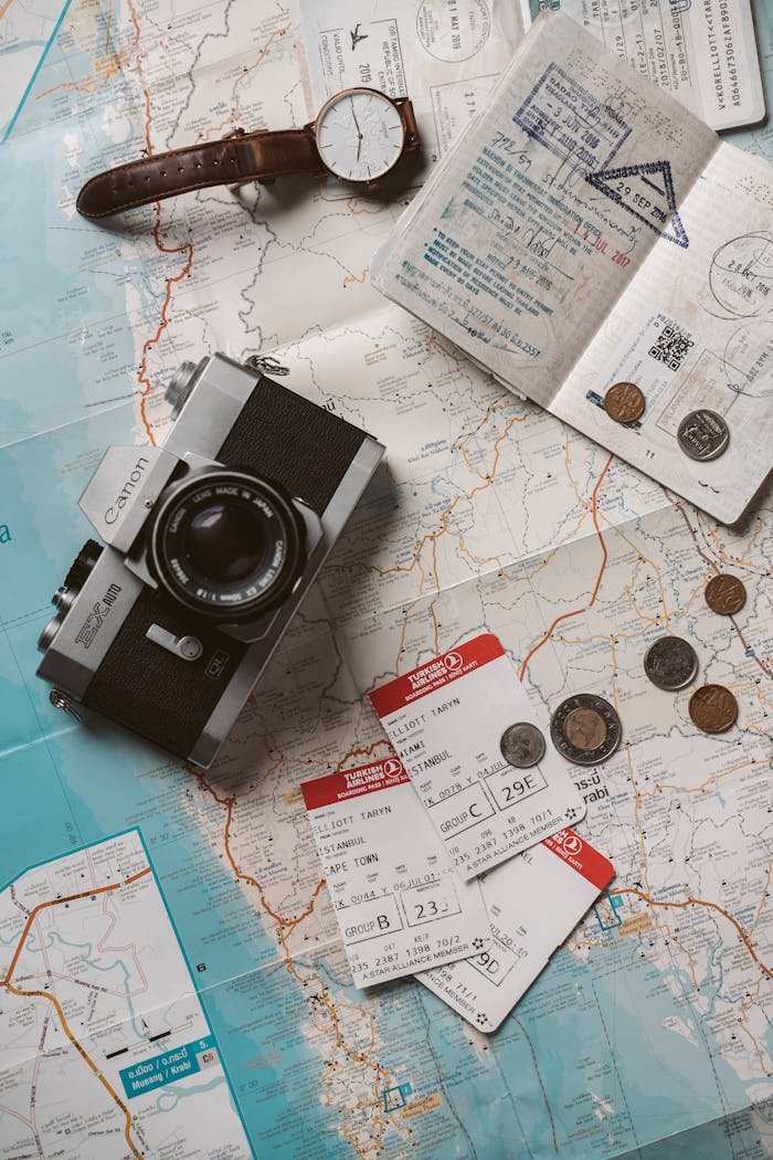 who-we-are Flat lay travel essentials including passports, tickets, and a vintage camera on a world map.